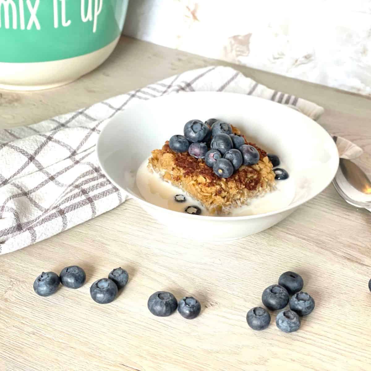 baked oatmeal in bowl with milk and blueberries