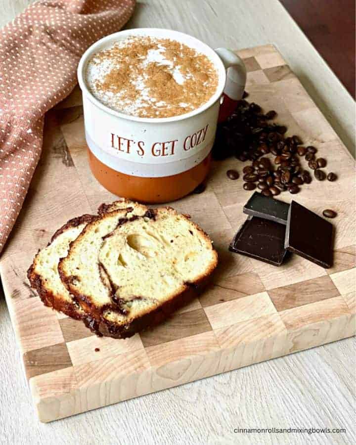 hazelnut latte on board with babka bread, coffee beans and chocolate