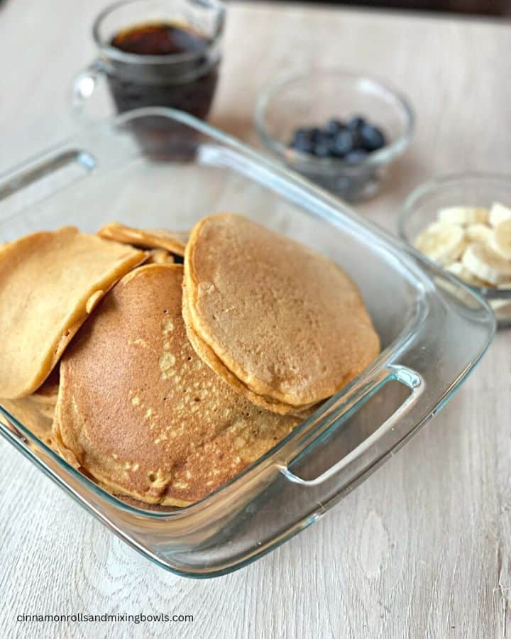 fresh kamut pancakes in glass pan with toppings in the background