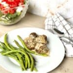 Easy low carb Swedish meatballs in cream sauce on plate with green beans and salad