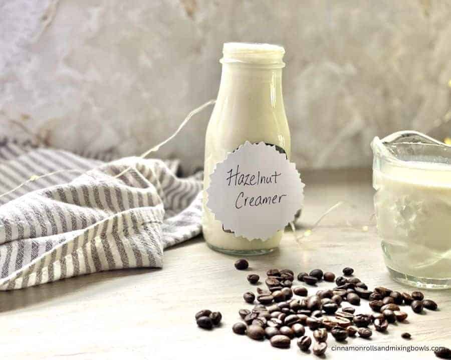 homemade hazelnut coffee creamer in jar with coffee beans on the counter