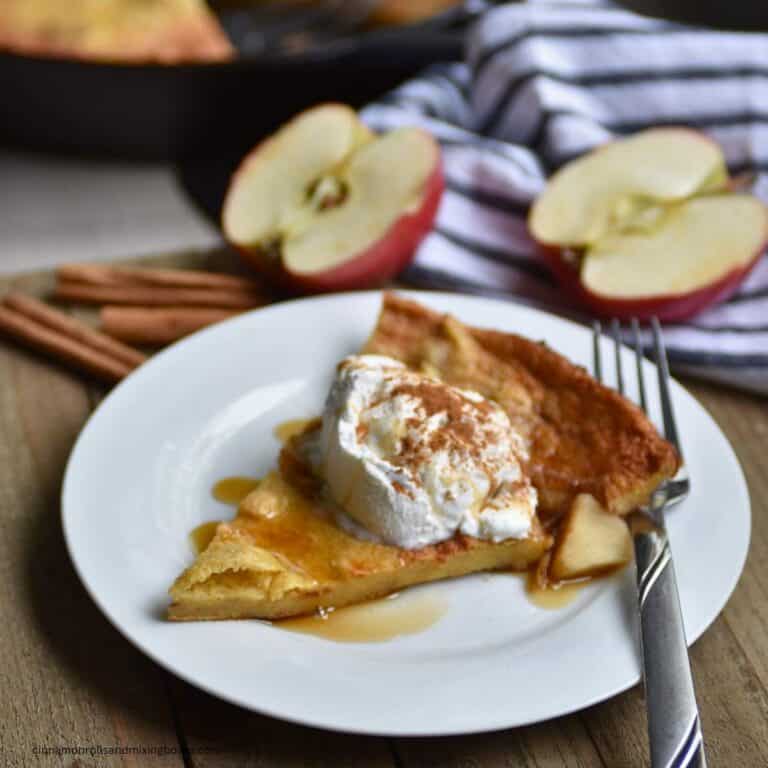 Kamut Apple German Pancake sitting on plate with whipped topping and drizzled with maple syrup