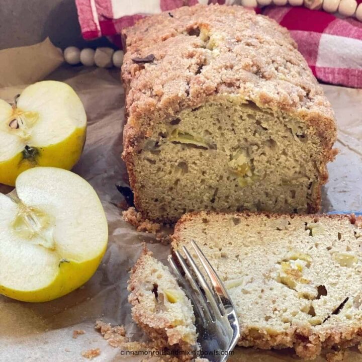 Sourdough Dutch apple bread loaf sitting on parchment paper with sliced apple next to it
